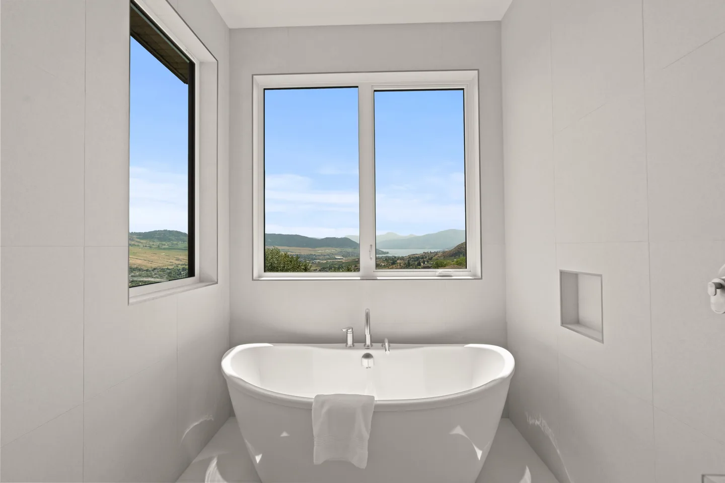 Freestanding soaker tub beneath a view window